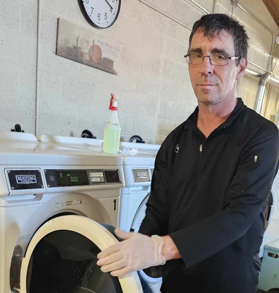 Employee cleaning and sanitizing washing machines