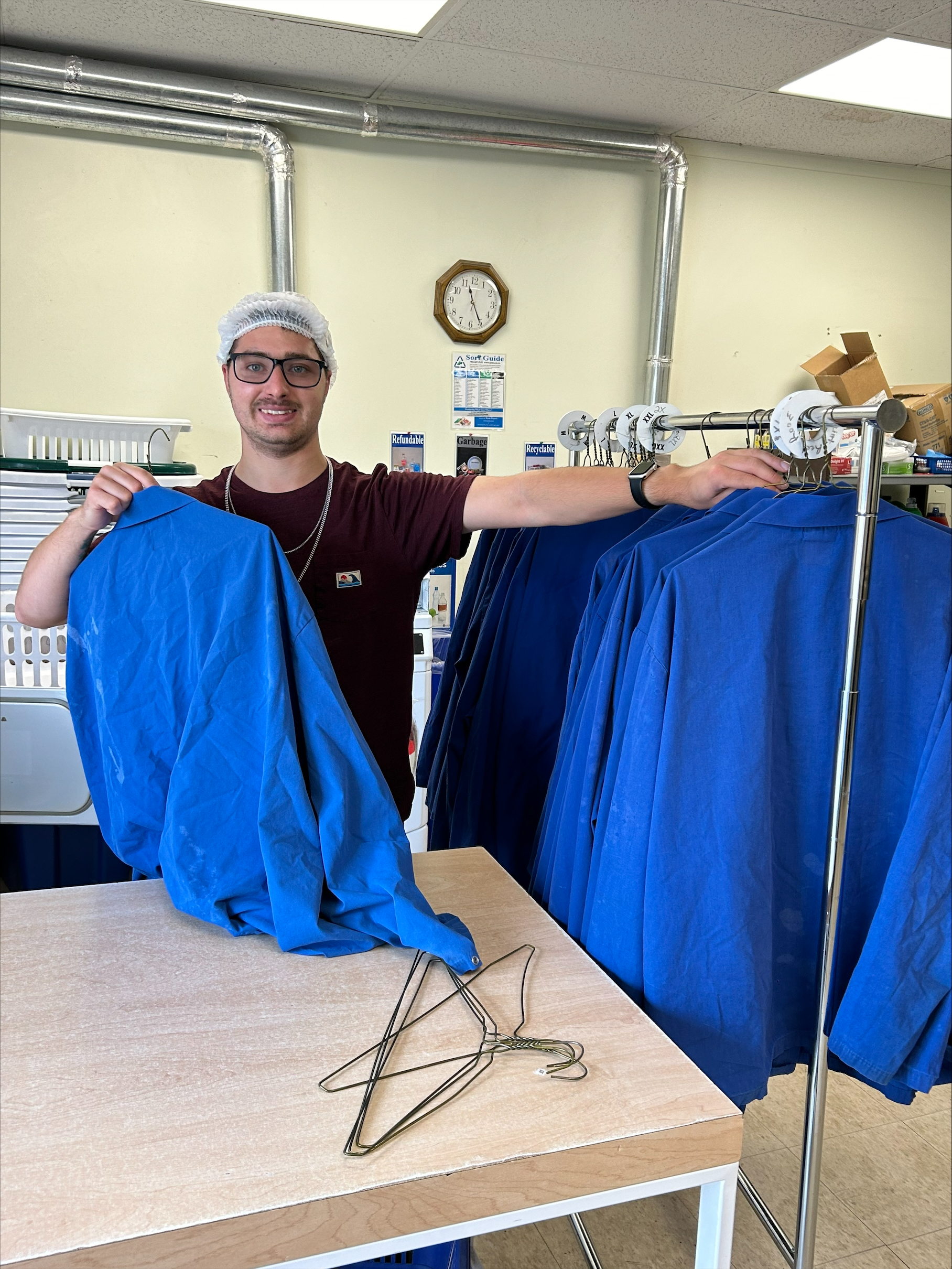 Employee smiling as he hangs clothes on rack